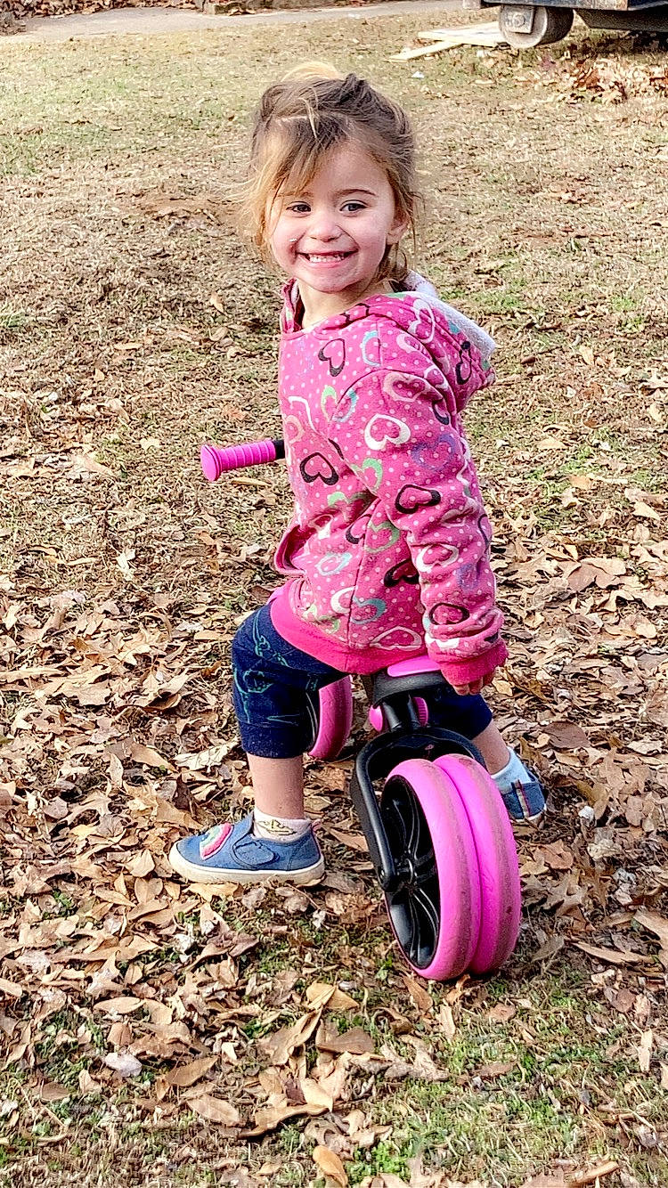 Laikyn is registered to the contest to win money with this photo: automotive_tire, baby_toddler_clothing, bicycle_tire, eye, face, fun, grass, happy, head, joy, magenta, people_in_nature, person, pink, purple, riding_toy, smile, sneakers, tire, toddler