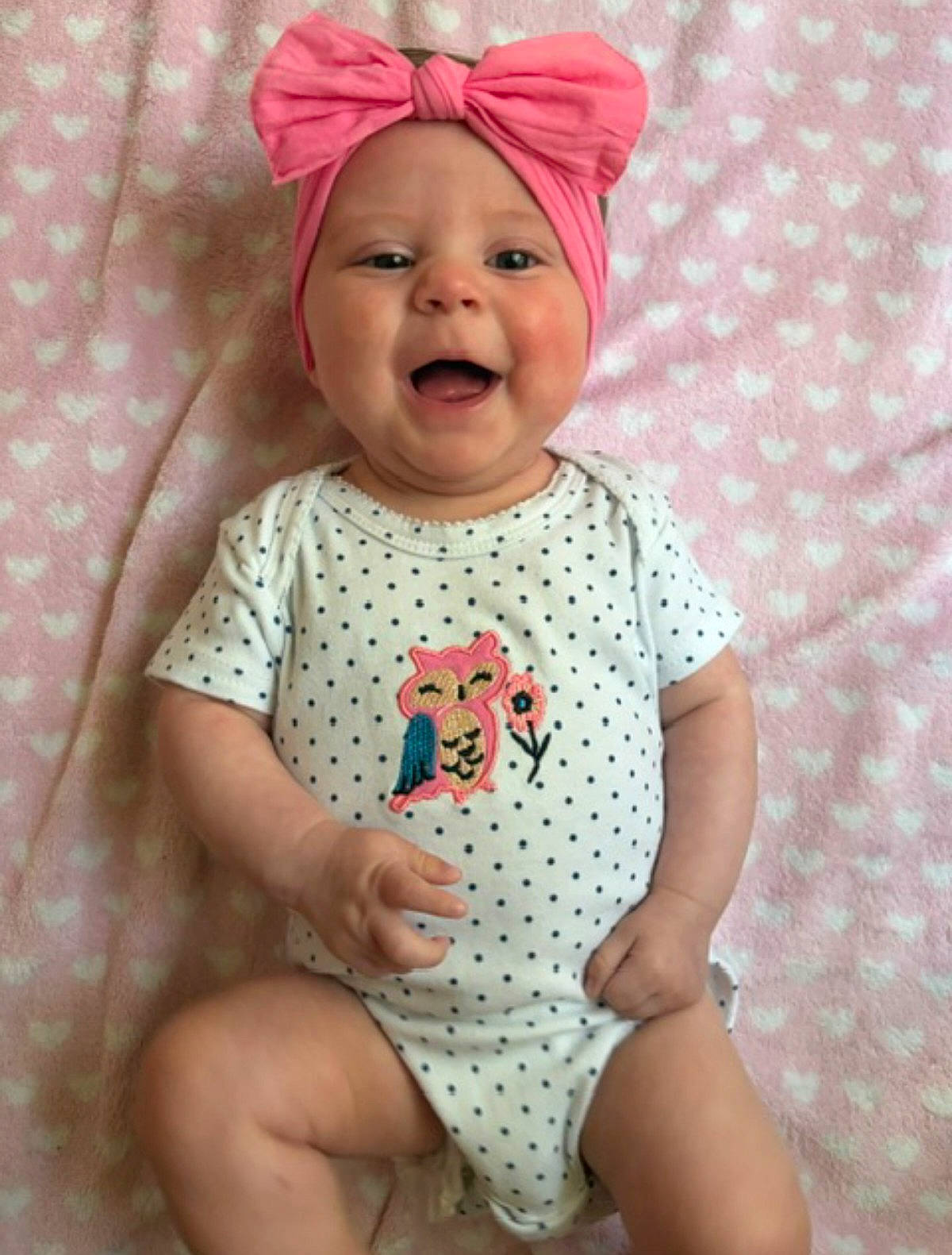 Brynlee Dallas joined the competition — help win amazing prizes! baby, blanket, child, closeup, cute, eyes, face, happy, headband, heart_pattern, indoor, infant, lying_down, onesie, open_mouth, photography, pink_bow, polka_dot_outfit, portrait, smiling