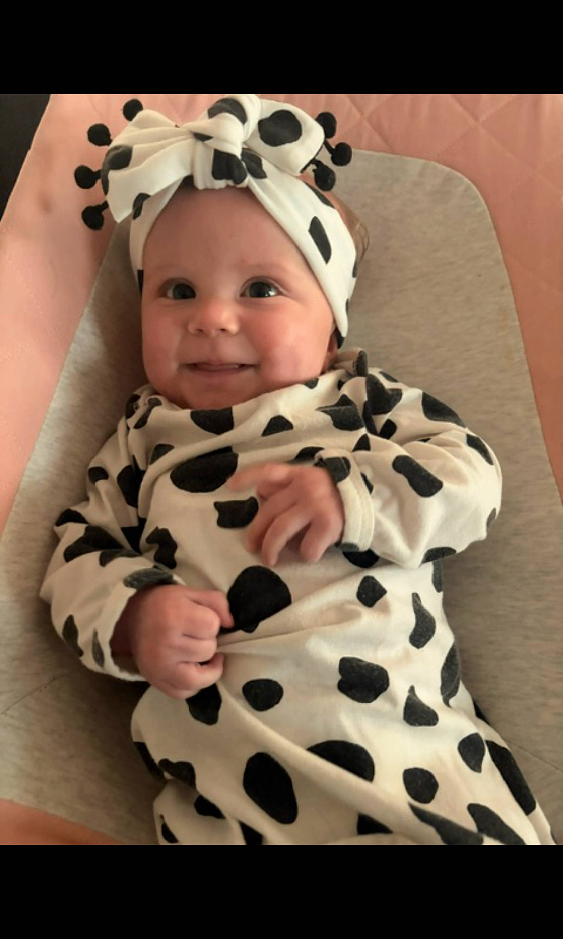 Brynlee Dallas joined the competition — help win amazing prizes! baby, black_and_white, blanket, bow, changing_pad, child, cow_print, cute, eyes, face, hands, happy, headband, indoor, infant, lying_down, onesie, photography, portrait, smiling