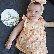 Violette participe au concours pour gagner de l'argent avec cette photo : 3_months_sign, baby, background, blue_pants, bow, child, clothing, cute, dress, fabric, face, happy, headband, infant, lying_down, peach, person, portrait, skin, smiling