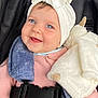 baby, child, blue_eyes, headband, white_bow, pink_sweater, car_seat, seatbelt, plush_toy, smiling, happy, cute, infant, portrait, close_up, indoor, soft_texture, cozy, clothing, person