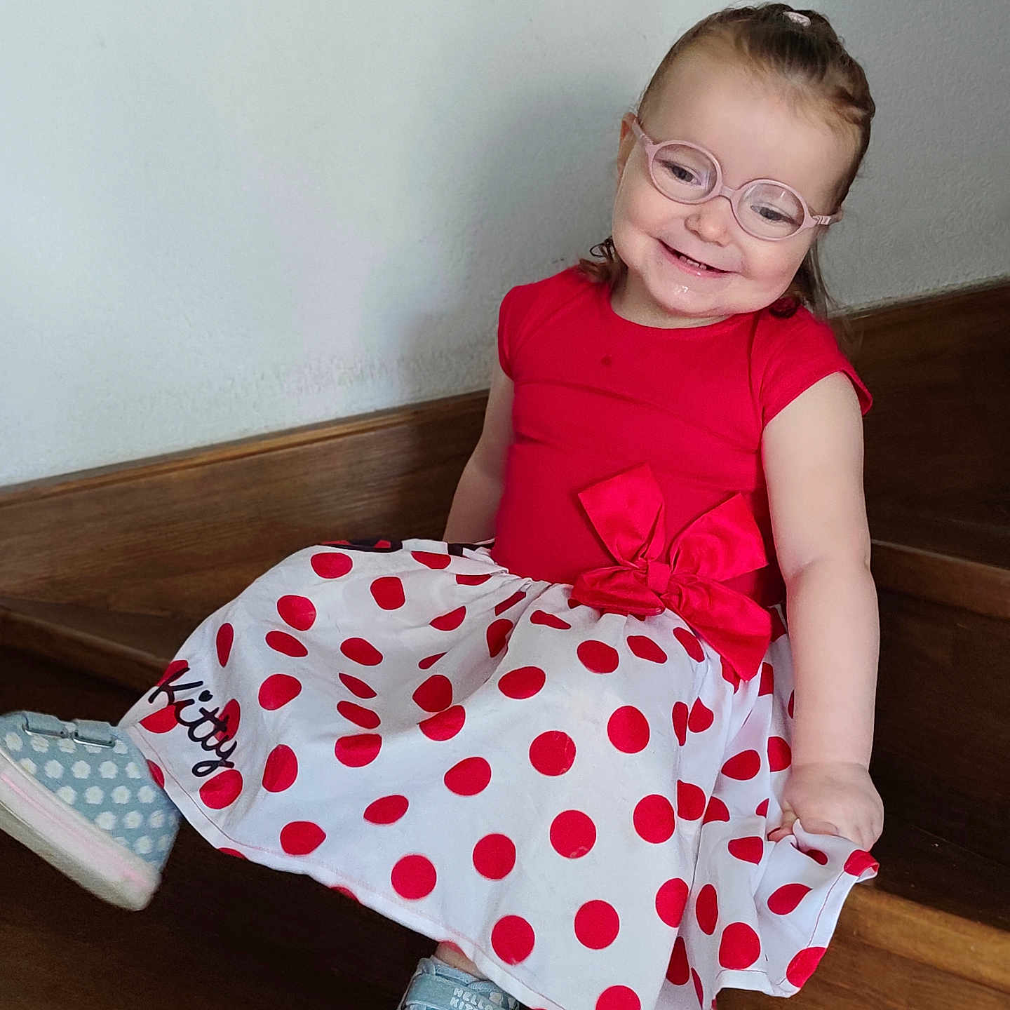 Mya participe au concours pour gagner de l'argent avec cette photo : child, girl, glasses, red_clothing, polka_dot_skirt, sitting, stairs, smile, happy, casual_shoes, indoor, portrait, cute, fashion, young, person, wood, glasses_frame, footwear, playful