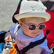 Mya participe au concours pour gagner de l'argent avec cette photo : toddler, child, hat, sunglasses, toy, stroller, red, white, outdoor, sunlight, smile, baby, clothing, seatbelt, person, play, cute, summer, headwear, accessory