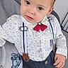 child, toddler, boy, polka_dot_shirt, red_bow_tie, suspenders, spiky_hair, indoor, couch, blanket, stairs, curious_expression, casual_pose, furniture, person, portrait, young_child, home, clothing, fashion