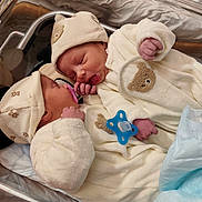 Leandro participe au concours pour gagner de l'argent avec cette photo : newborn, baby, infant, hospital, bassinet, pacifier, hat, blanket, sleeping, cute, cozy, clothing, bear_design, hand, face, person, toddler, indoors, bed, resting