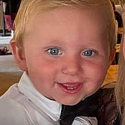 Greyson is registered to the contest to win money with this photo: toddler, child, smiling, indoor, portrait, blond_hair, blue_eyes, formal_wear, bow_tie, white_shirt, face, person, happy, close_up, background_people, social_event, casual, young_child, cute, celebration