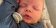 Logan is registered to the contest to win money with this photo: baby, sleeping, pacifier, blanket, blue_clothing, infant, soft_texture, face, peaceful, resting, child, cute, newborn, portrait, indoors, cozy, hand, skin, nap, comfort