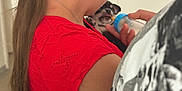 Aïko participe au concours pour gagner de l'argent avec cette photo : person, puppy, baby_bottle, feeding, indoor, red_clothing, long_hair, glasses, hand, close_up, black_and_white, patterned_clothing, animal, pet, nurturing, caring, young_animal, cute, holding, human