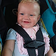 Arayah is registered to the contest to win money with this photo: baby, child, car_seat, curly_hair, blonde, smiling, blue_eyes, pink_bib, safety_harness, seatbelt, infant, cute, portrait, happy, indoors, clothing, seat, person, young_child, secure