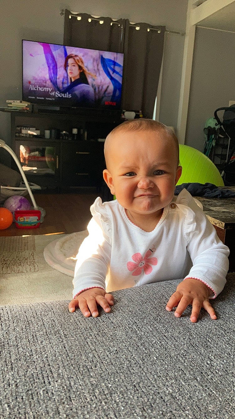Soleil is registered to the contest to win money with this photo: baby, baby_toddler_clothing, cable_television, cheek, child, comfort, crawling, floor, flooring, fun, hardwood, iris, joy, output_device, person, skin, smile, standing, television, television_set