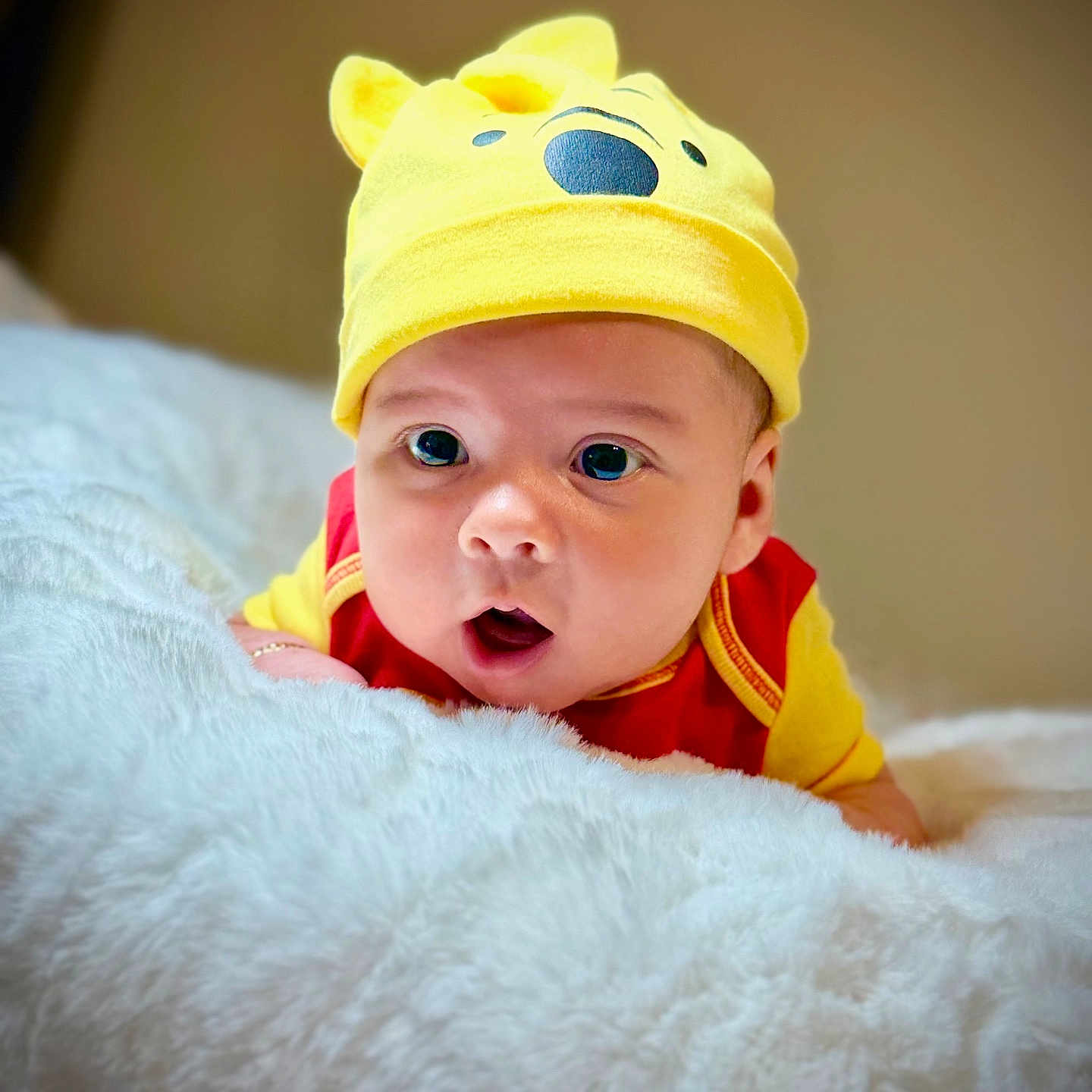 Matheo Santiago is registered to the contest to win money with this photo: adorable, baby, child, closeup, cute, expression, face, fluffy_blanket, hat, headwear, indoors, infant, lying_down, portrait, red_clothing, soft_texture, surprised, wide_eyes, yellow_hat, young_child