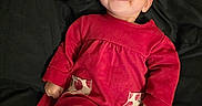 Amyra is registered to the contest to win money with this photo: baby, child, infant, red_dress, headband, bow, smile, tongue_out, patterned_leggings, cherry_pattern, black_blanket, cute, happy, indoors, portrait, person, lying_down, young_child, cozy, clothing