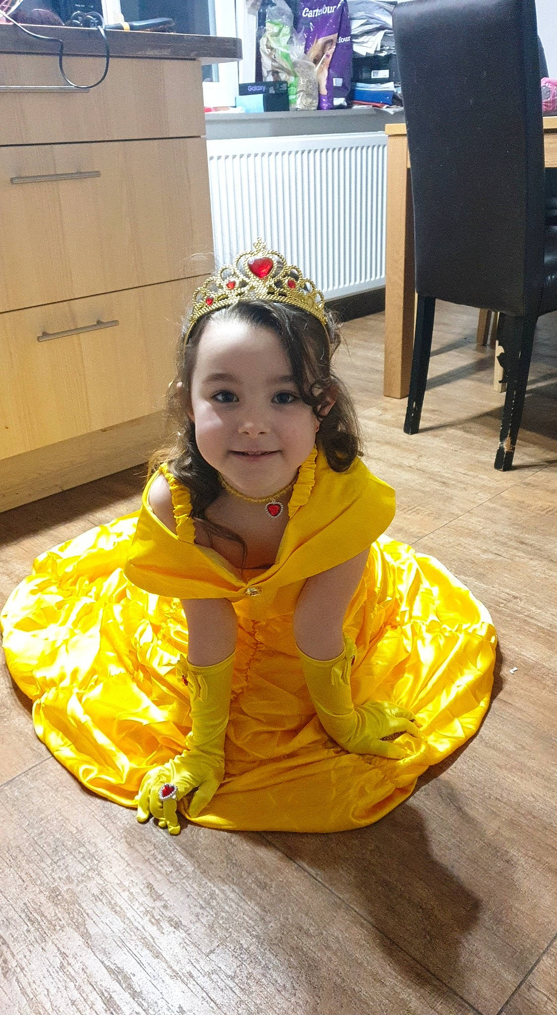 Ilana participe au concours pour gagner de l'argent avec cette photo : cabinetry, chair, child, costume, event, face, fashion_accessory, flooring, fun, happy, joy, leisure, person, personal_protective_equipment, room, sitting, smile, toddler, tradition, yellow