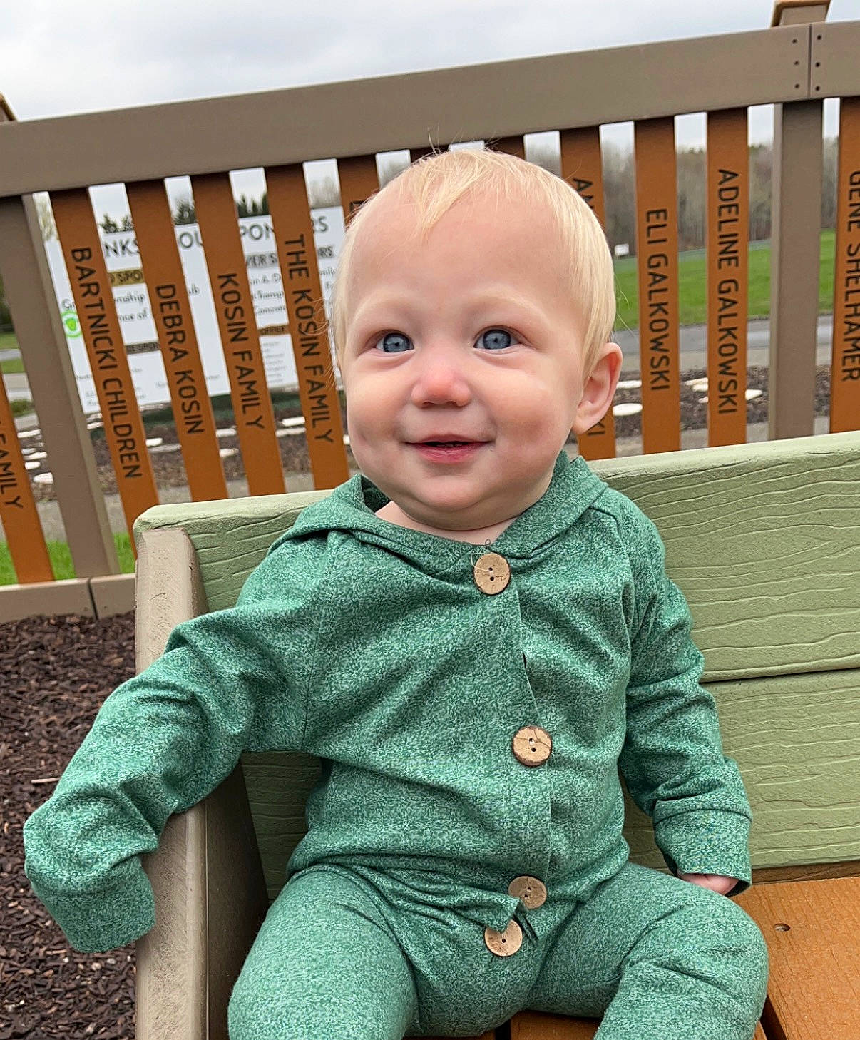 Evander is registered to the contest to win money with this photo: baby, baby_products, baby_toddler_clothing, button, cheek, child, doll, eye, face, grass, happy, joy, laugh, pattern, person, room, sitting, sleeve, smile, t_shirt