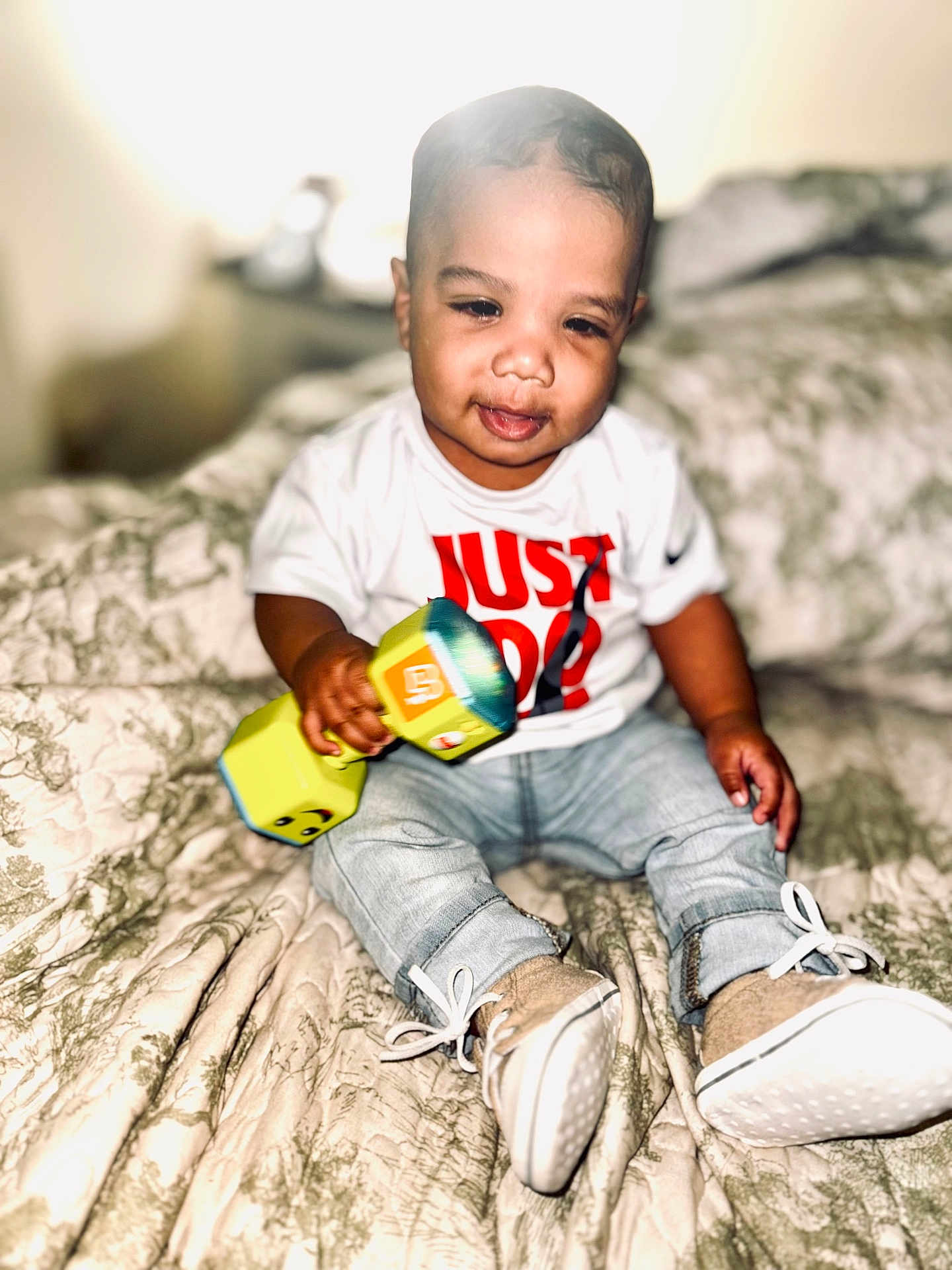 Raydon joined the competition — help win amazing prizes! baby, child, toy, dumbbell, jeans, sneakers, shirt, bed, blanket, indoor, person, smile, cute, sitting, footwear, young, infant, clothing, home, portrait
