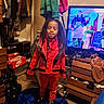 blue_rug, carpet, casual, child, clothes, clothing, curly_hair, door, dresser, furniture, hanger, indoor, person, red_jacket, room_interior, screen, shoes, standing, television, young