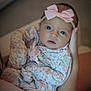 Kennedy is registered to the contest to win money with this photo: baby, infant, child, headband, bow, onesie, floral, clothing, person, face, eyes, hand, holding, portrait, indoor, soft_light, cute, newborn, expression, skin