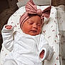 newborn, baby, sleeping, headband, pink_bow, white_clothing, blanket, floral_pattern, infant, cute, peaceful, soft_texture, child, portrait, indoors, resting, cozy, small_hands, wrapped, toddler