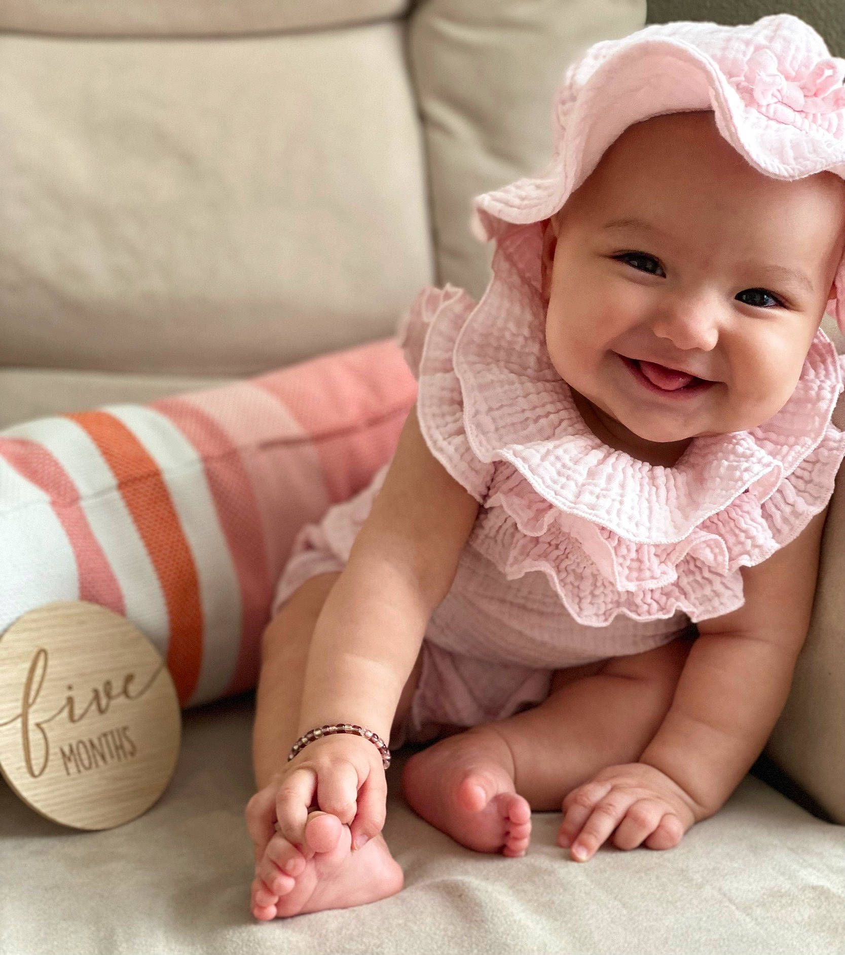 Milan is registered to the contest to win money with this photo: arm, baby, baby_toddler_clothing, comfort, dress, finger, gesture, hand, happy, headwear, human_body, joy, mammal, person, photograph, pink, skin, sleeve, smile, textile