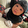 baby, infant, child, portrait, close_up, face, eyes, wide_eyed, looking_at_camera, black_bonnet, black_clothing, socks, heart_pattern, cushion, indoor, home, seated, adorable, photography, baby_fashion