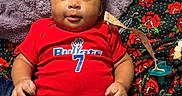 Sevynn joined the competition — help win amazing prizes! baby, infant, child, portrait, smiling, lying_down, red_outfit, sports_jersey, number_seven, blanket, cozy, pacifier, sock, bed, indoor, close_up, face, curly_hair, happy, family_photo