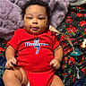 baby, infant, child, portrait, smiling, lying_down, red_outfit, sports_jersey, number_seven, blanket, cozy, pacifier, sock, bed, indoor, close_up, face, curly_hair, happy, family_photo