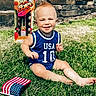 toddler, child, grass, lawn, blue_jersey, usa, number_10, flag, american_flag, fireworks, box, mohawk, smiling, sunny, outdoor, summer, happy, barefoot, playing, portrait