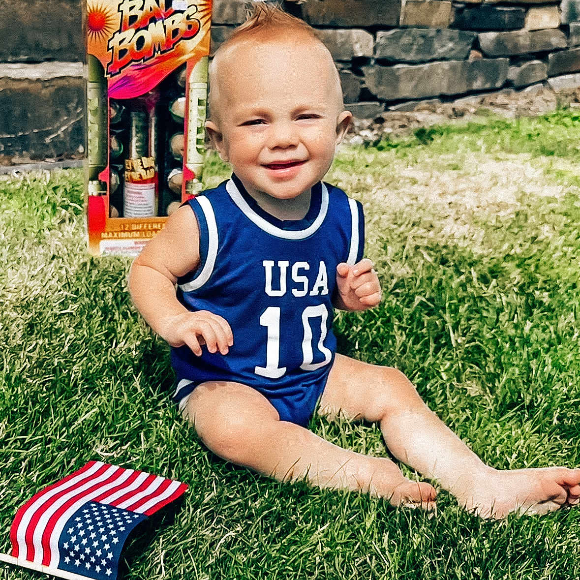 Lager Dean is registered to the contest to win money with this photo: toddler, child, grass, lawn, blue_jersey, usa, number_10, flag, american_flag, fireworks, box, mohawk, smiling, sunny, outdoor, summer, happy, barefoot, playing, portrait