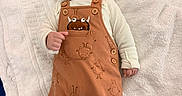 Tyler is registered to the contest to win money with this photo: baby, brown_clothing, button, child, clothing, curly_hair, cute, happy, indoor, infant, lying_down, monster_print, overalls, playful, portrait, skin, small_hands, smiling, towel, white_towel