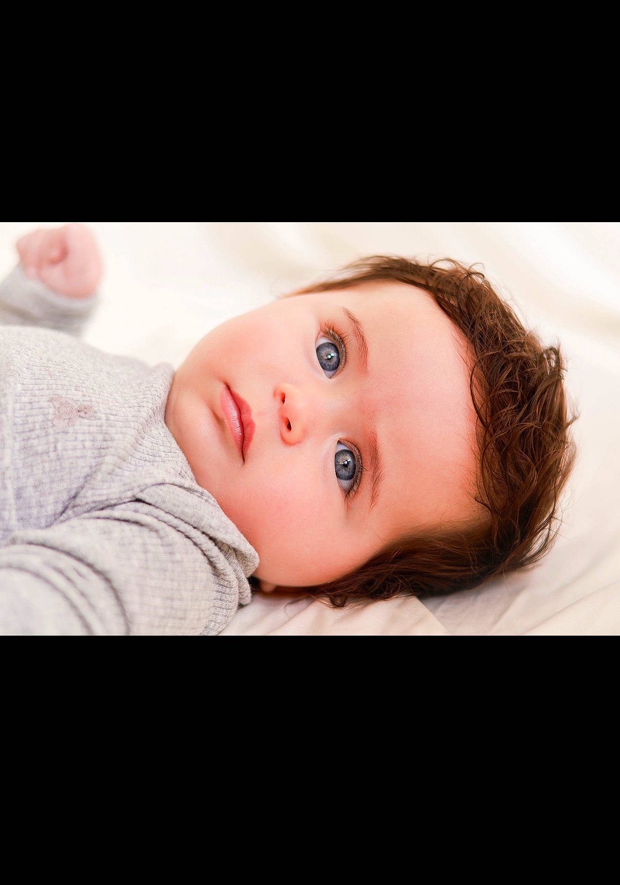 baby, blue_eyes, child, close_up, clothing, cozy, cute, expressionless, face, hair, indoors, infant, lying_down, newborn, person, portrait, skin, sleepy, soft_light, young