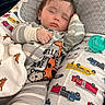 baby, sleeping, pajamas, striped_clothing, pacifier, pillow, vehicles, blanket, bed, cute, child, infant, rest, cozy, soft_lighting, indoor, peaceful, comfort, face, hand