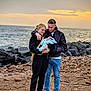 Morgan participe au concours pour gagner de l'argent avec cette photo : family, baby, couple, beach, sunset, ocean, rocks, blanket, casual_clothing, glasses, jeans, sneakers, outdoor, love, parenthood, nature, sky, sand, affection, portrait