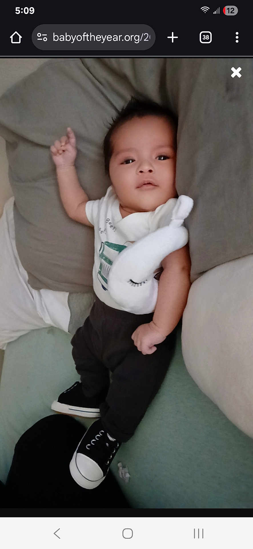 Giovanni joined the competition — help win amazing prizes! baby, bed, black_pants, casual_clothing, child, comfortable, cute, indoor, infant, looking_at_camera, lying_down, pillow, plush_toy, relaxed, resting, small_shoes, sneakers, soft_toy, white_shirt, young_child