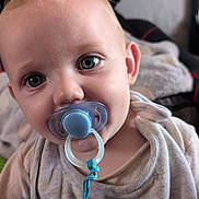 Henry is registered to the contest to win money with this photo: baby, child, pacifier, blue_pacifier, close_up, face, eyes, shirt, bear_design, toddler, indoors, soft_light, curious, cute, infant, clothing, person, portrait, young_child, expression