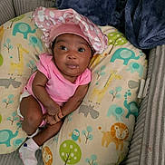 Autumn is registered to the contest to win money with this photo: baby, infant, child, portrait, sitting, pink_outfit, pink_hat, wide_eyes, indoors, couch, pillow, blanket, animal_pattern, elephant, giraffe, lion, owl, nursery, sock, happy