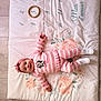 baby, child, pink_clothing, striped_outfit, headband, smiling, lying_down, playmat, floral_pattern, numbers, wooden_floor, white_shoes, cute, infant, person, indoor, soft_mat, toy_ring, happy, portrait