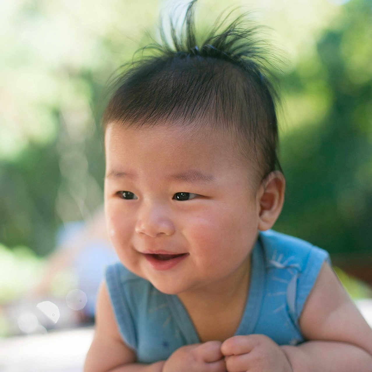 Anton joined the competition — help win amazing prizes! baby, background_blur, blanket, blue_clothing, child, cute, daylight, face, greenery, hair, hands, happy, infant, lying_down, nature, outdoor, portrait, skin, smile, young