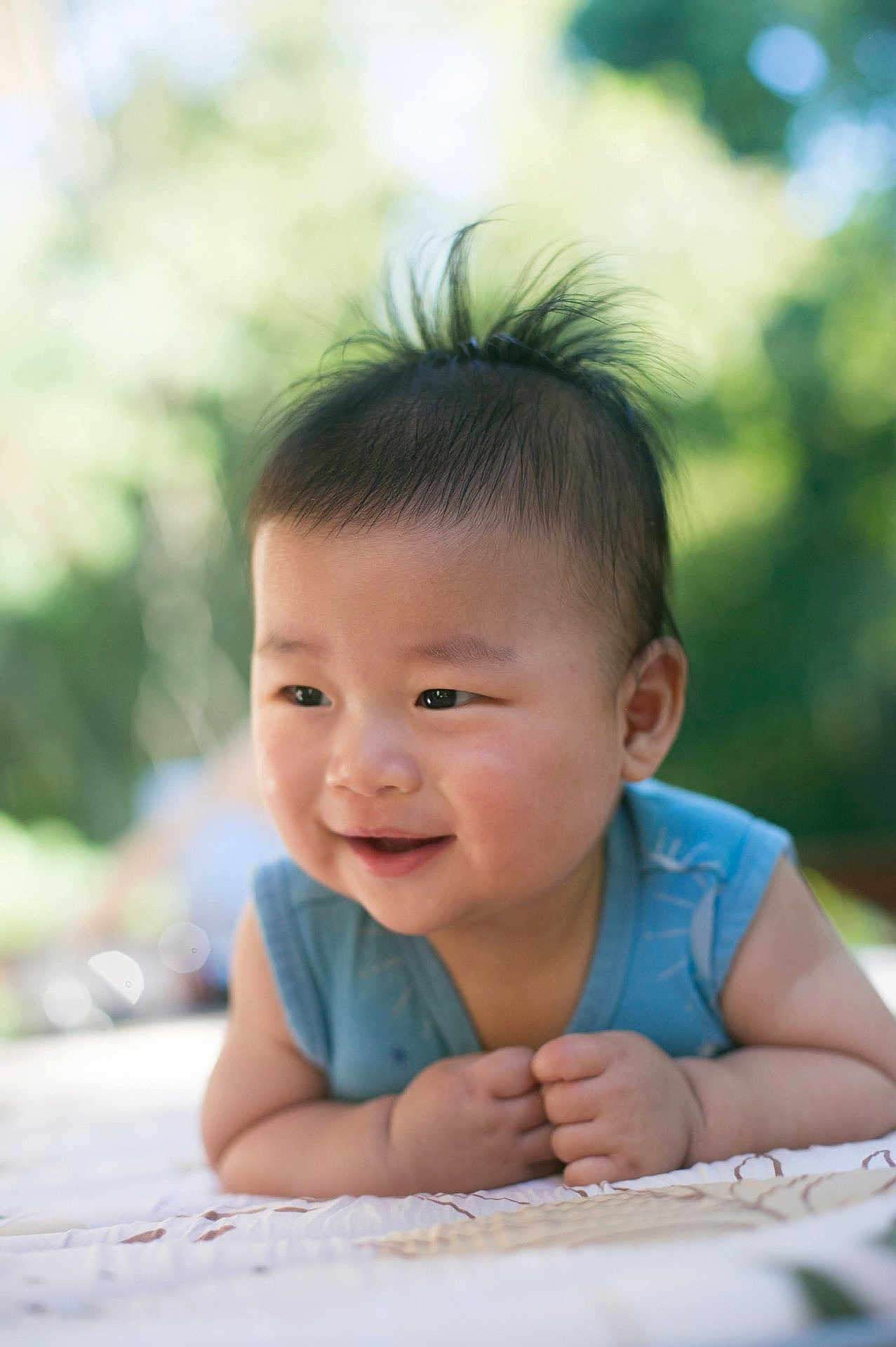 Anton joined the competition — help win amazing prizes! baby, child, smile, happy, face, portrait, outdoor, nature, greenery, infant, cute, young, skin, hair, blue_clothing, blanket, daylight, background_blur, hands, lying_down