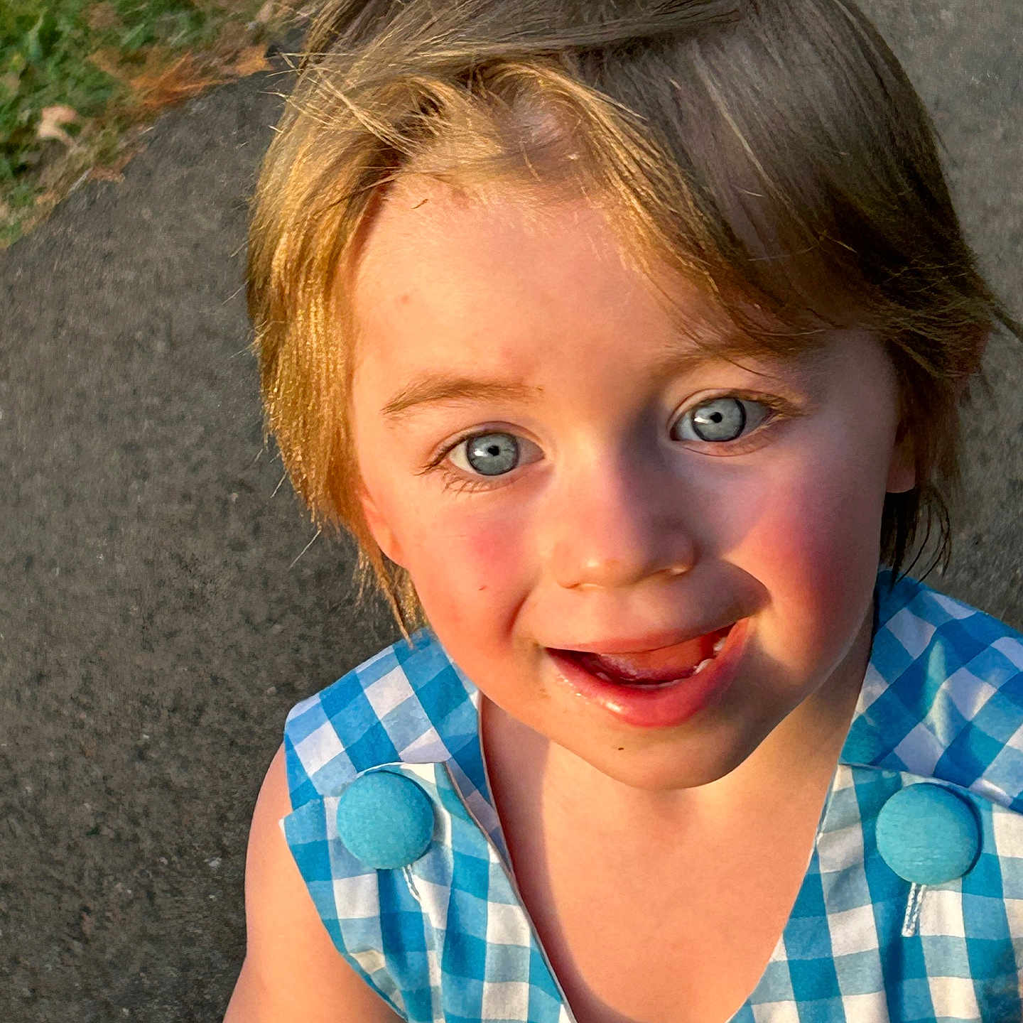 Rory is registered to the contest to win money with this photo: blond_hair, blue_eyes, button, child, clothing, cute, dress, expression, face, grass, happy, outdoor, pavement, person, portrait, skin, smiling, sunlight, toddler, young
