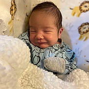 Juan joined the competition — help win amazing prizes! newborn, baby, blanket, sleeping, smiling, mittens, blue_outfit, patterned_background, lion_pattern, crown_pattern, soft_texture, cozy, infant, portrait, closeup, cute, resting, indoors, child, peaceful