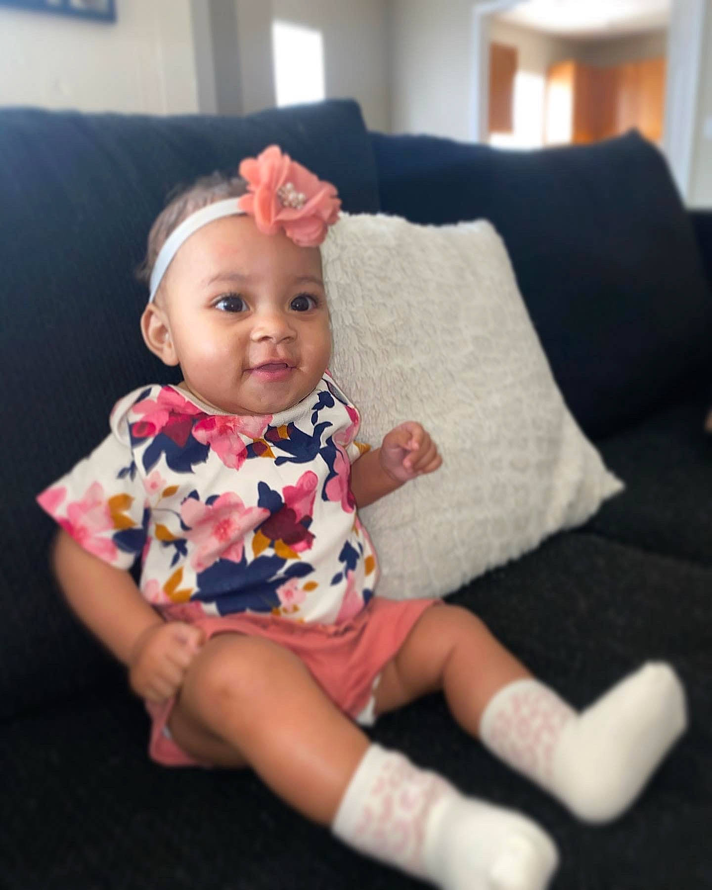 Amira joined the competition — help win amazing prizes! baby, baby_toddler_clothing, cheek, child, couch, ear, eye, hair_accessory, headpiece, headwear, human_body, living_room, person, picture_frame, pillow, pink, sitting, skin, sock, studio_couch