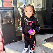 Amor joined the competition — help win amazing prizes! child, city, colorful, curly_hair, doorway, fashion, jacket, outdoor, portrait, reflection, smiling, sneakers, standing, steps, storefront, street, sunlight, toddler, toy, tracksuit