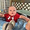 baby, infant, child, red_shirt, activity_center, toy_mouse, outdoor, wooden_deck, house_siding, plastic_toys, baby_seat, face, expression, cute, play, childhood, person, bright, daylight, smile