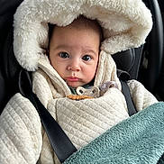 Mao participe au concours pour gagner de l'argent avec cette photo : baby, child, infant, car_seat, blanket, coat, hood, face, wide_eyes, curious, pensive, straps, safety, soft_texture, warm_clothing, indoor, portrait, close_up, cute, bundle