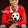 person, dog, dalmatian, pet, animal, portrait, red_sweater, jeans, short_hair, white_hair, watch, earrings, studio, black_background, sitting, smiling, hand, face, leash, friendly