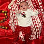 baby, infant, holiday, christmas, festive, red, white, blanket, ornaments, number_two, snowflake_pattern, pajamas, clothing, fabric, cute, lying_down, face, person, indoors, celebration