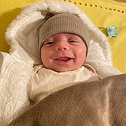 Emir Ali a rejoint le concours — aidez-le/la à gagner de superbes lots ! baby, smile, hat, blanket, pacifier, yellow_mat, white_jacket, cozy, infant, child, warm_clothing, indoor, cute, face, headwear, wrapped, happy, lying_down, soft_texture, comfort