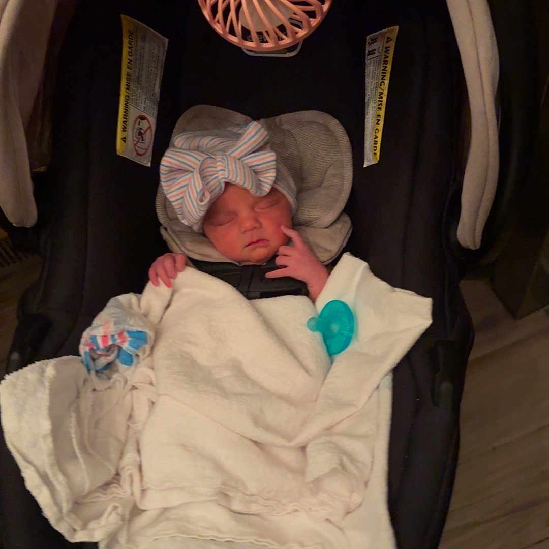 Lakelyn joined the competition — help win amazing prizes! newborn, baby, infant, sleeping, car_seat, blanket, bow, headband, pacifier, portable_fan, parent_hand, indoor, portrait, face, eyes_closed, bundled, clothing, safety_straps, wood_floor, cozy