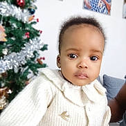 Syrielle participe au concours pour gagner de l'argent avec cette photo : baby, child, portrait, sweater, white_clothing, indoor, christmas_tree, decoration, holiday, blurred_background, face, cute, young_child, knitwear, person, expression, closeup, cozy, festive, holiday_season