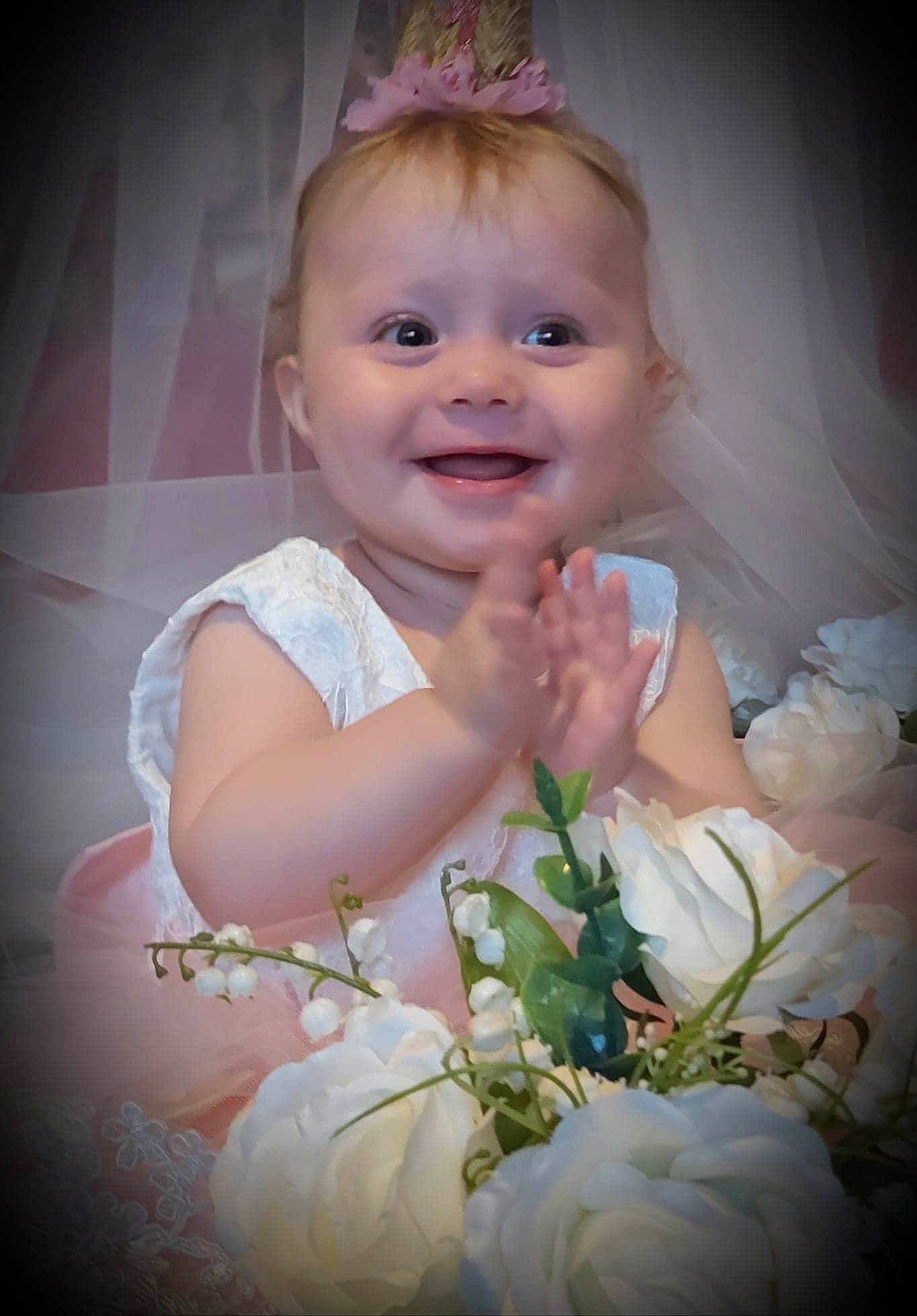 Courtney is registered to the contest to win money with this photo: baby, cheek, child, eye, face, facial_expression, flower, fun, hair_accessory, happy, head, iris, joy, nose, person, photography, plant, portrait, skin, smile